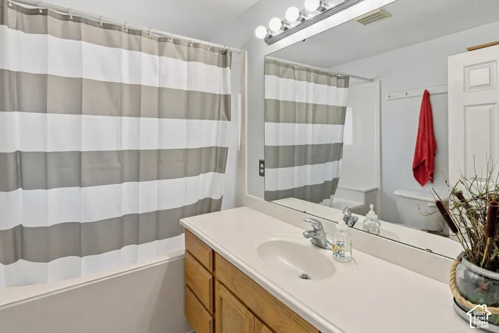 Spa-inspired bathroom featuring a wood-finish vanity with dual-sink white countertop, polished chrome faucetry, and large framed mirror with integrated lighting