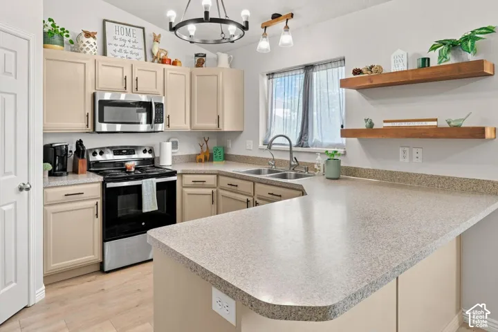 Bright kitchen featuring cream cabinetry, stainless steel appliances, and a quartz-style composite countertop with waterfall edge on the island