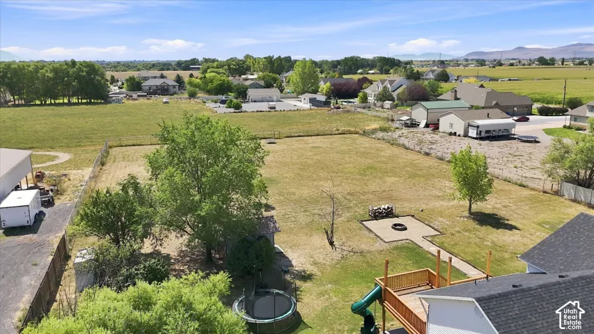 Expansive backyard featuring a designated fire pit area, mature trees, and a wooden deck
