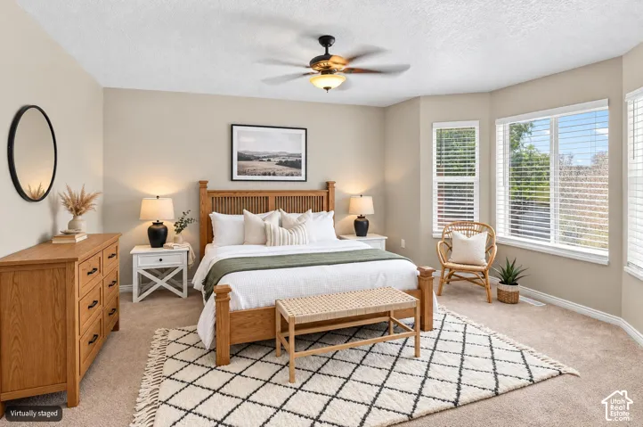 Carpeted room featuring a ceiling fan with integrated lighting, multiple windows with blinds, and neutral wall tones