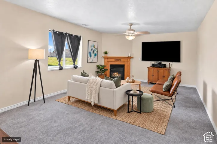 Bright, open living room showcasing hardwood-finish flooring, a gas fireplace with wood mantel surround, and generous ceiling height
