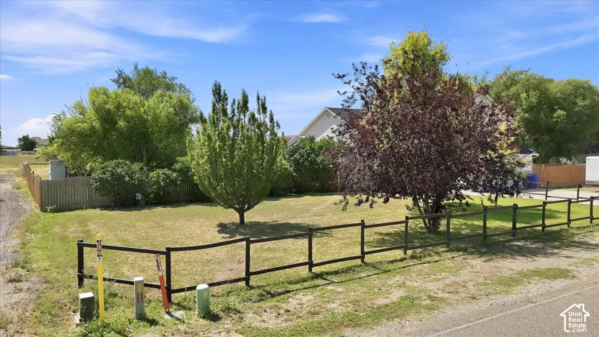 Expansive lot featuring a partial wood fence, mature trees, and a grass lawn