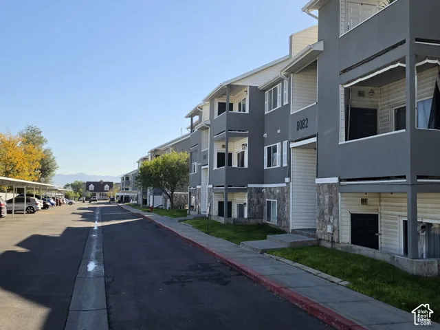 Multi-story building with gray siding, stone veneer accents, and individual balconies