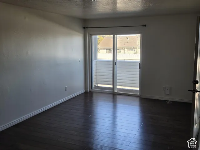 Wood-finish flooring, white painted walls, sliding glass door, and a private balcony with horizontal fencing