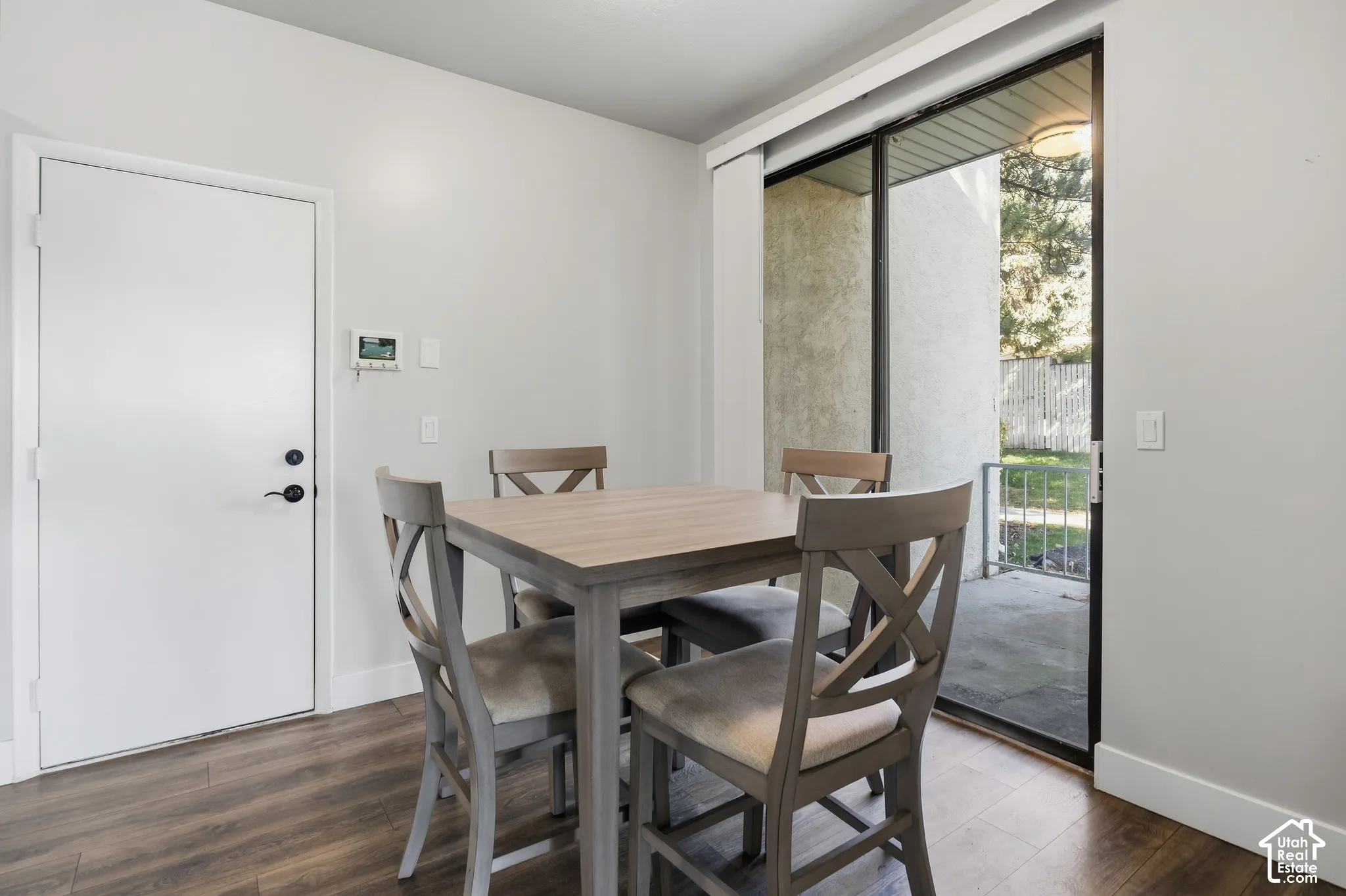 Wood-finish flooring, white walls, and a sliding glass door providing access to a concrete patio