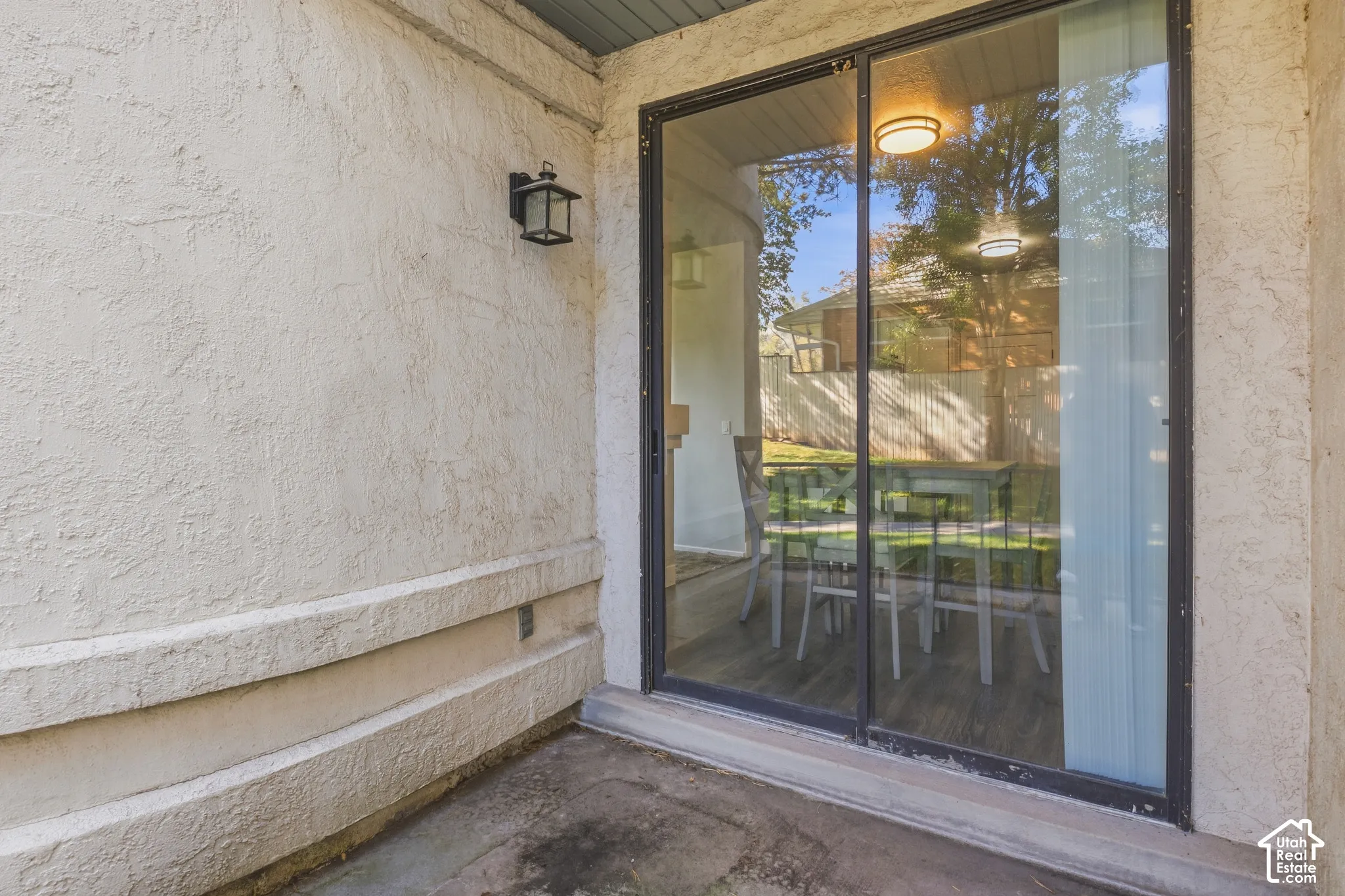 Sliding glass door access to an exterior patio with stucco walls
