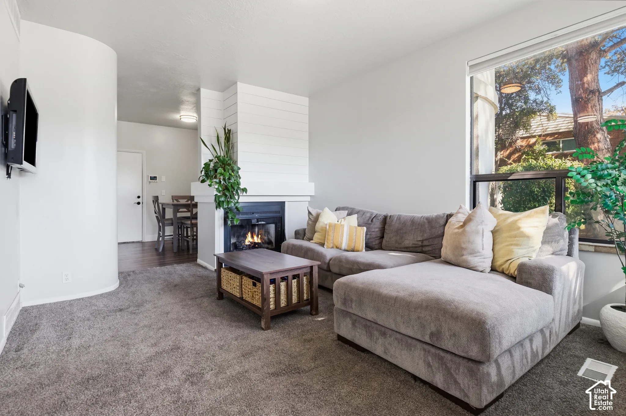 Living area featuring a fireplace with a shiplap accent wall, a large picture window, and carpeting