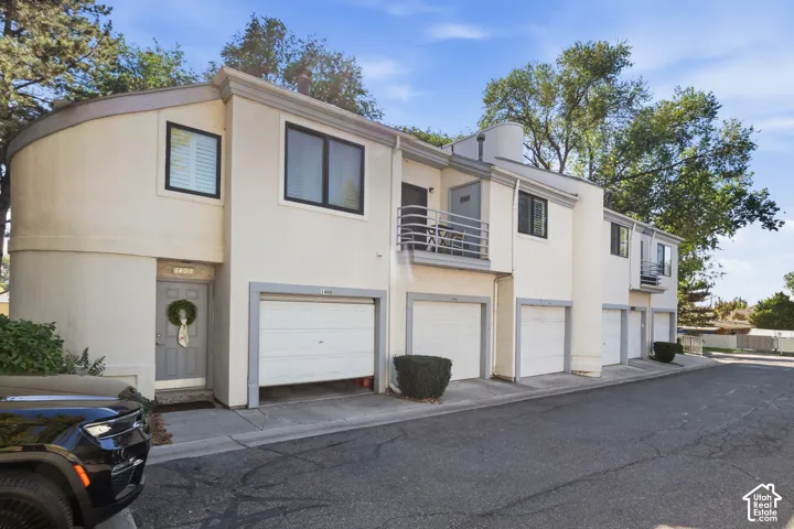 Stucco exterior with multiple garage bays, individual entry doors, and upper-level balconies