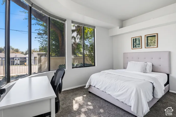 Curved bay window, multiple large windows with roller shades, recessed lighting, and carpeted flooring