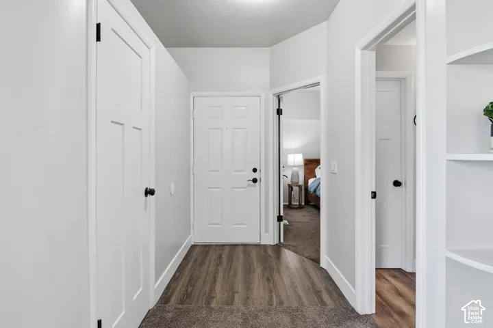 Bright hallway showcasing white six-panel doors with matte black hardware, wood-finish flooring, and built-in shelving with display space