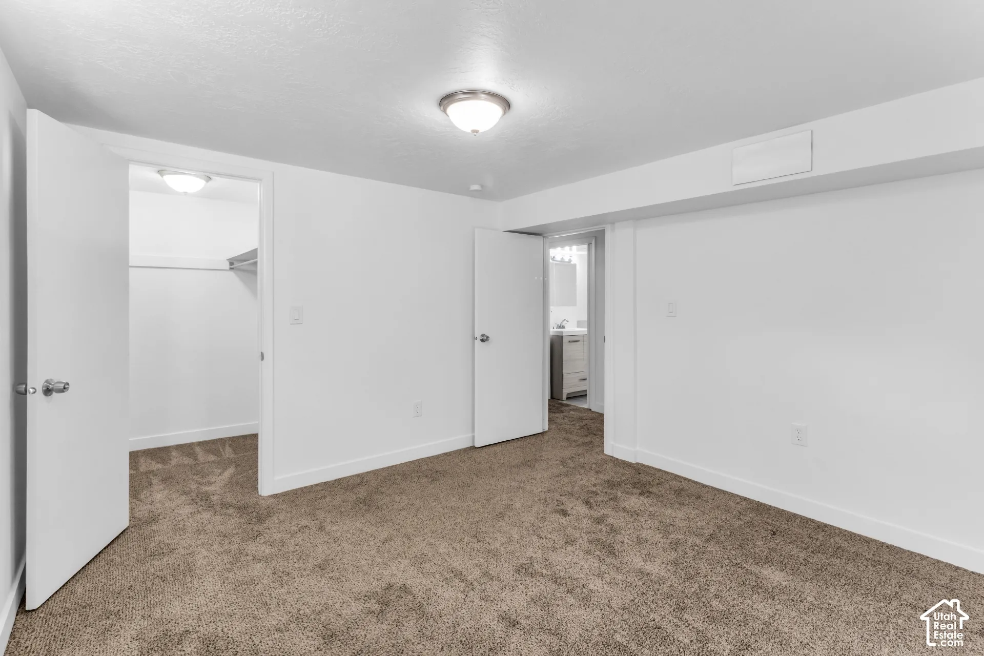 Spacious bedroom with neutral wall finishes, recessed ceiling lighting, and neutral-tone carpeting