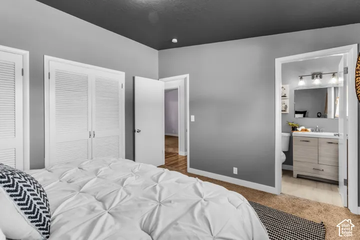 Louvered bi-fold closet doors, neutral wall color, recessed lighting, and a vanity with an integrated sink