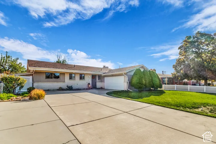 Concrete driveway, attached garage, low-pitched roof, brick and siding exterior, and established front landscaping