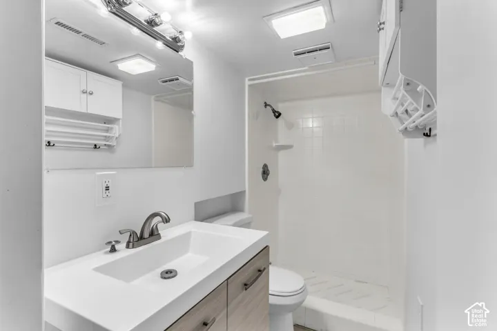 Modern bathroom featuring a floating wood-finish vanity with an integrated sink and quartz countertop, polished chrome faucet, framed mirror with integrated lighting, white subway tile surround in the walk-in shower with frameless glass enclosure, and rec