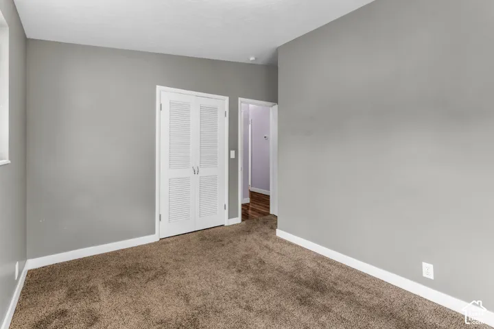 Wall-to-wall carpeting, light gray wall finish, white louvered bifold doors, and white trim molding