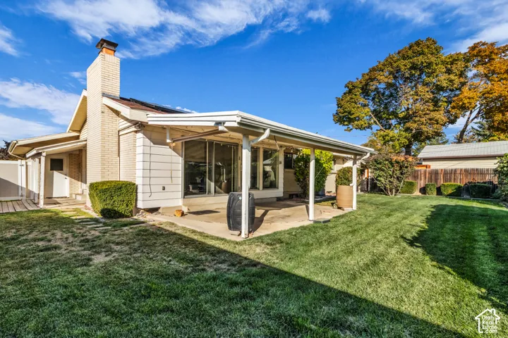 Expansive backyard featuring a covered patio, brick chimney, privacy fencing, and Imported grapes from Turkey with raised garden boxes.
