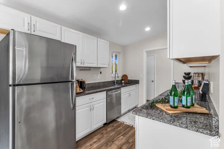 White cabinetry, stainless steel appliances, granite countertops, wood-finish flooring, and recessed lighting