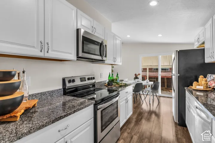 Kitchen featuring white cabinetry, granite-style countertops, stainless steel appliances, and wood-finish flooring