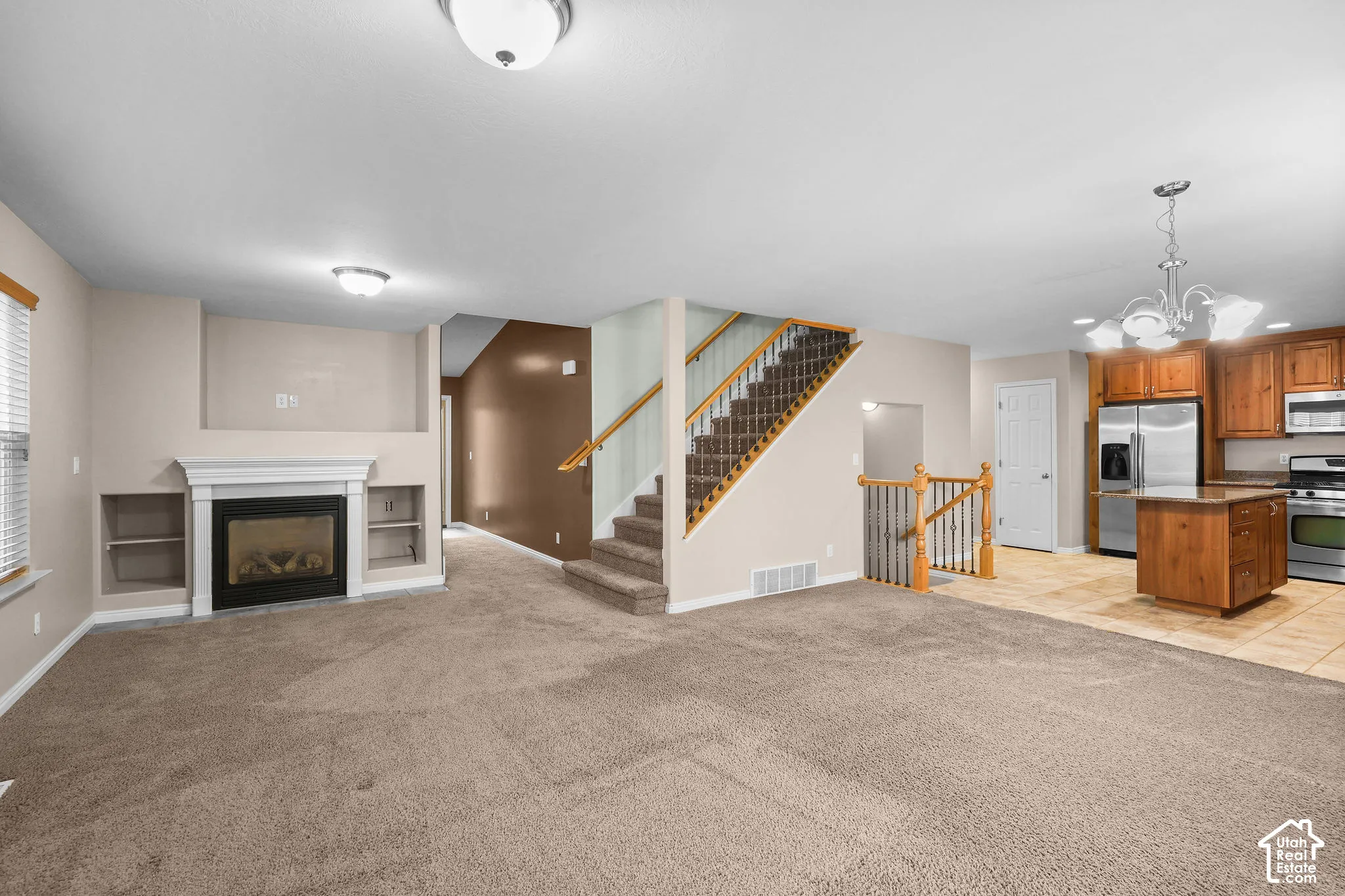 Carpeted living area with a fireplace featuring a white mantel and built-in shelving