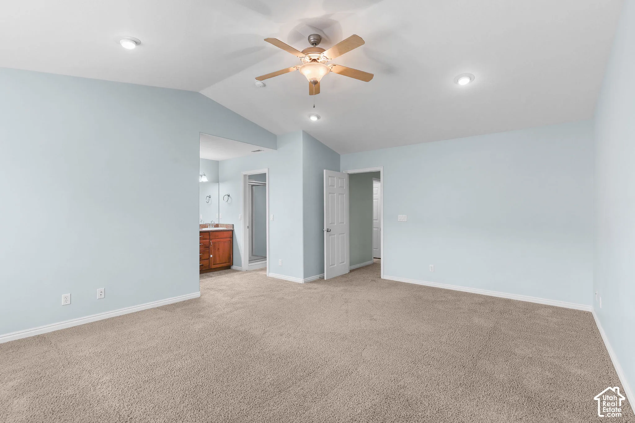 Recessed ceiling lights, ceiling fan with light fixture, carpeted flooring, wood-finish vanity with countertop, and a glass-enclosed shower