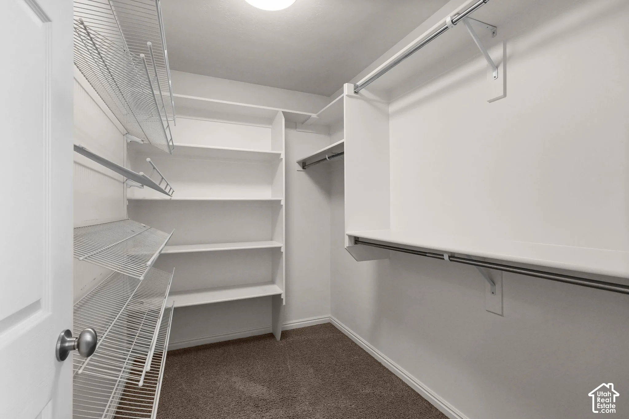 Spacious walk-in closet featuring multiple wire shelving units, hanging rod systems, and dark flooring throughout