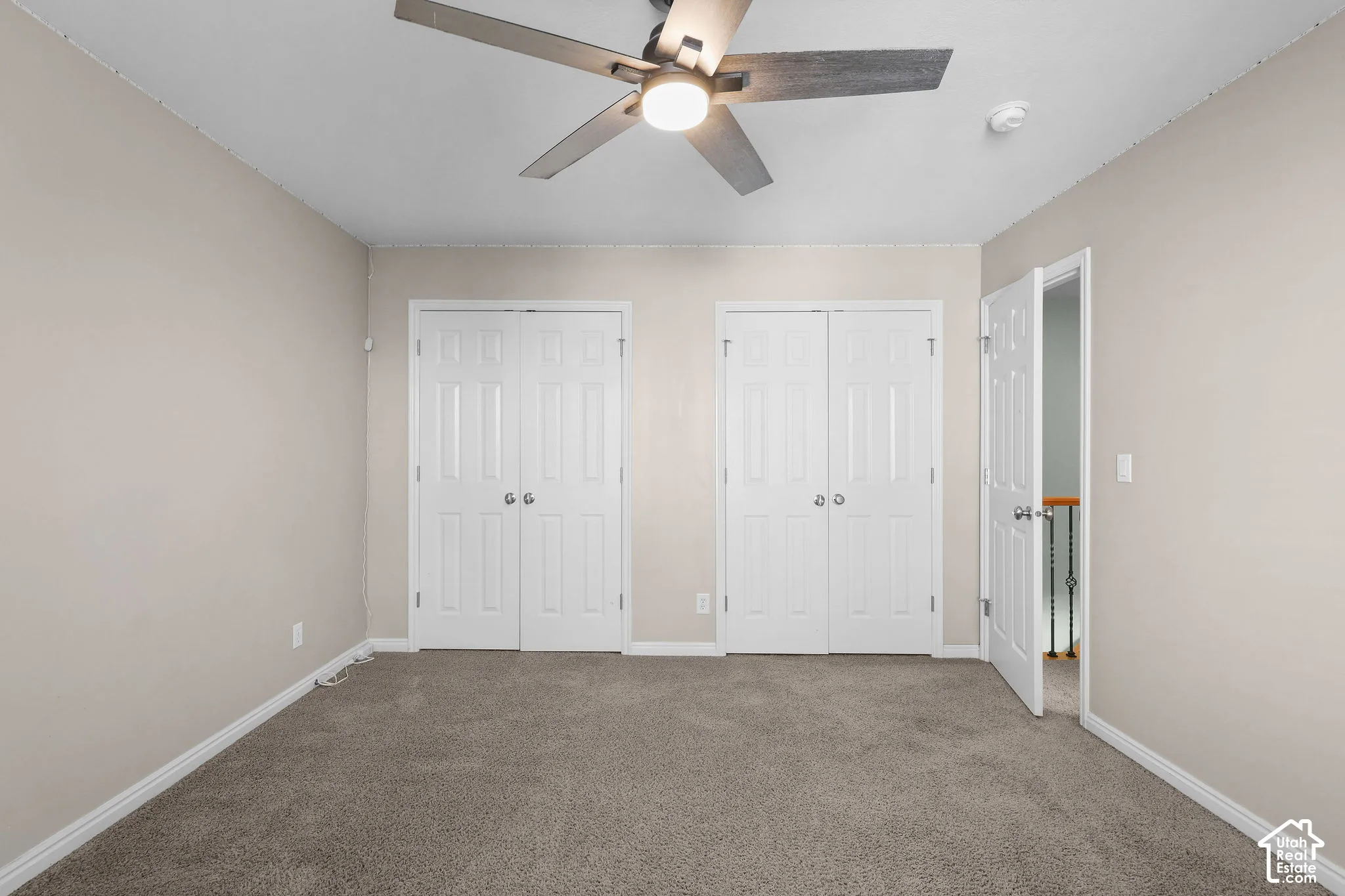 Neutral-toned walls, carpeted flooring, and a ceiling fan with integrated lighting
