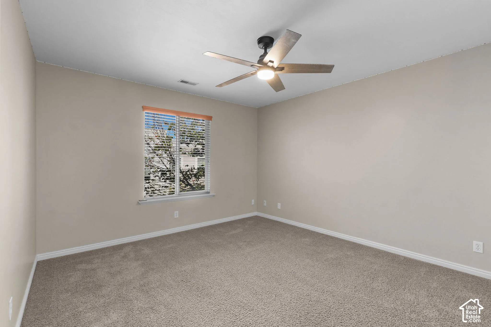 Carpeted room with a ceiling fan, a window with blinds, and neutral wall tones