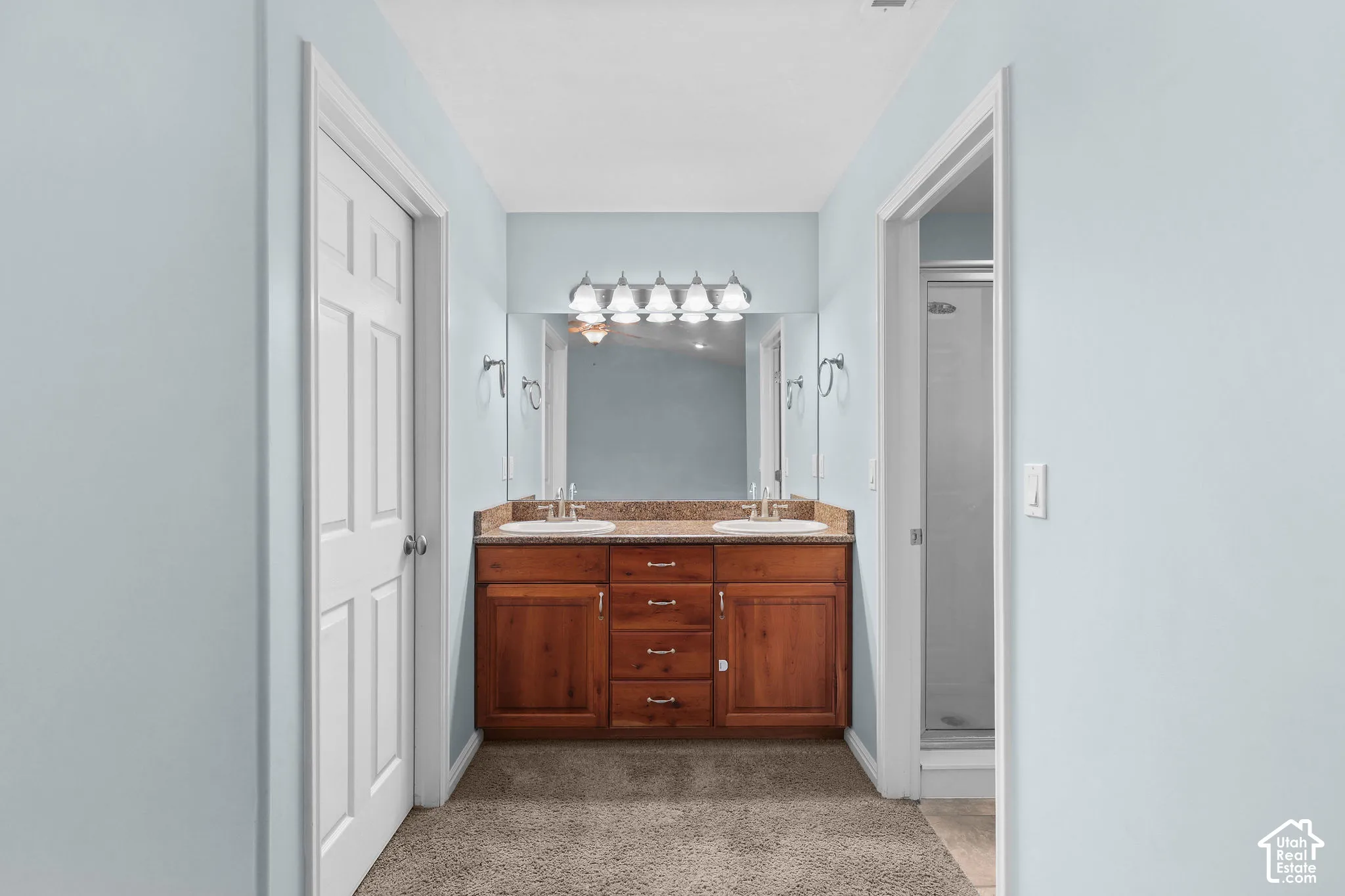 Double vanity with wood-finish cabinetry, dual undermount sinks, and a stone-finish countertop