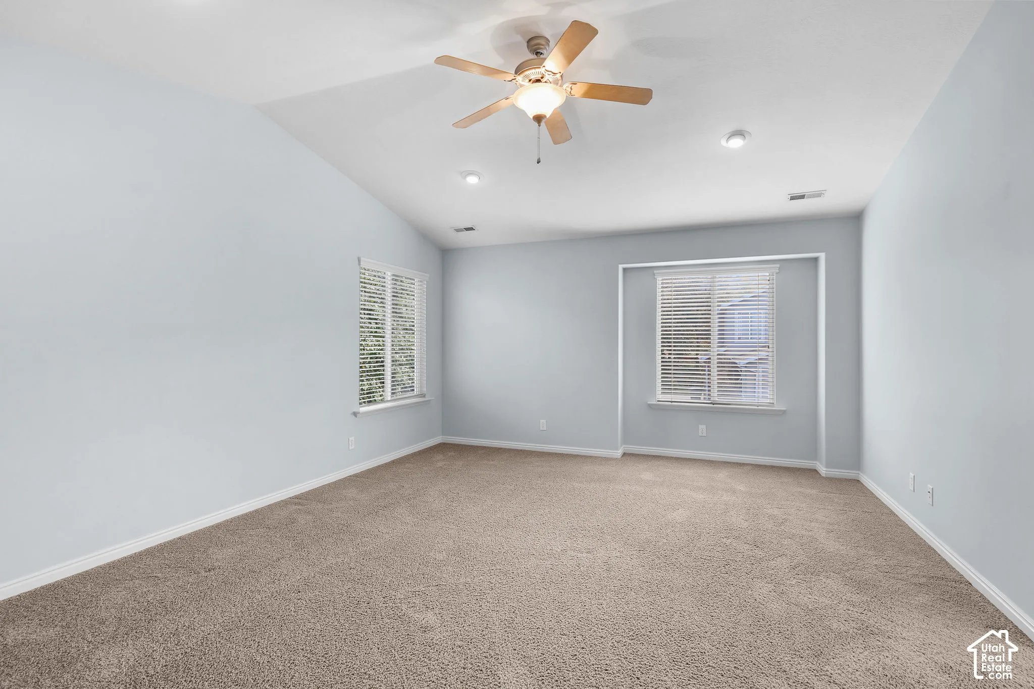 Carpeted flooring, vaulted ceiling, dual windows with blinds, recessed lighting, and a ceiling fan