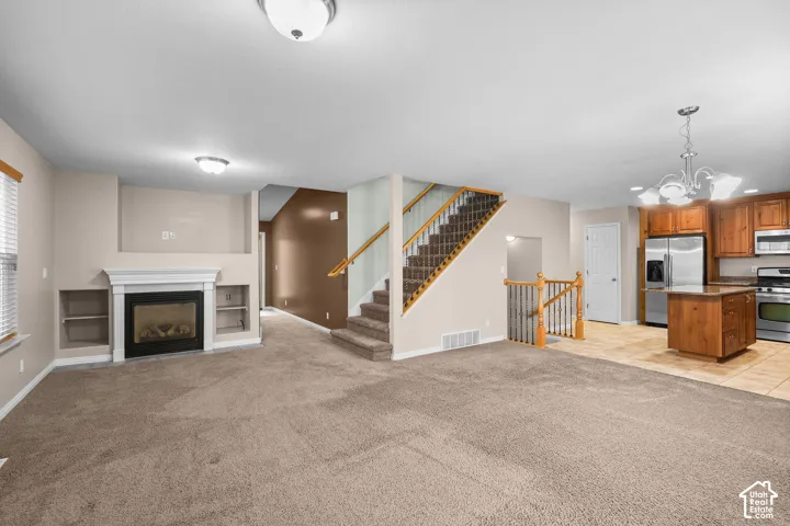 Carpeted living area with a fireplace featuring a white mantel and built-in shelving
