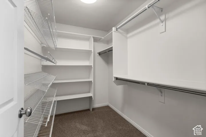 Spacious walk-in closet featuring multiple wire shelving units, hanging rod systems, and dark flooring throughout