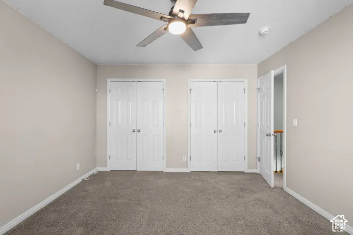 Neutral-toned walls, carpeted flooring, and a ceiling fan with integrated lighting