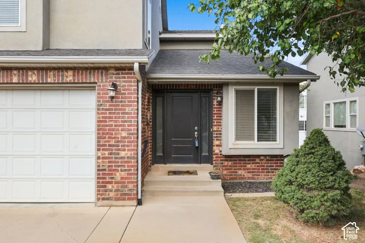 Brick and stucco exterior with an attached garage, covered entryway, and mature landscaping