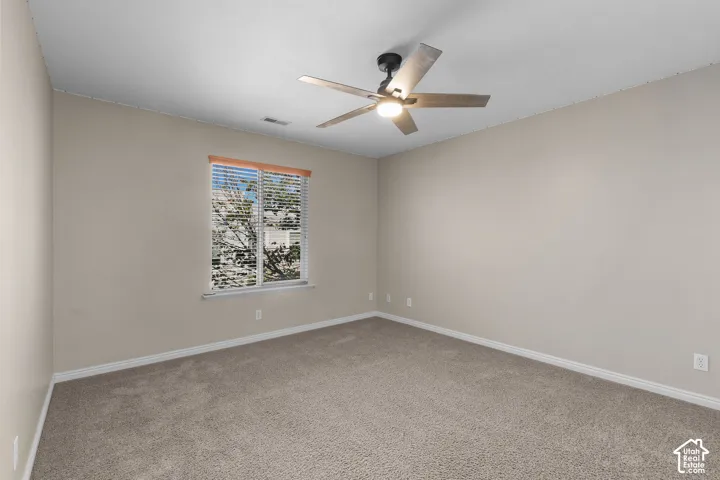 Carpeted room with a ceiling fan, a window with blinds, and neutral wall tones