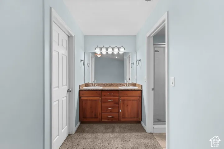 Double vanity with wood-finish cabinetry, dual undermount sinks, and a stone-finish countertop