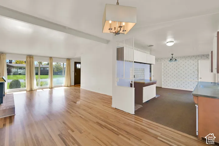 Vaulted ceiling, wood-finish flooring, full-light entry door, kitchen pass-through, and built-in cabinetry