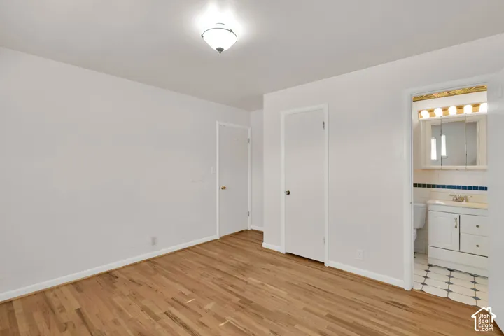 Wood-finish flooring with white baseboards, a flush-mount ceiling light, and white interior doors
