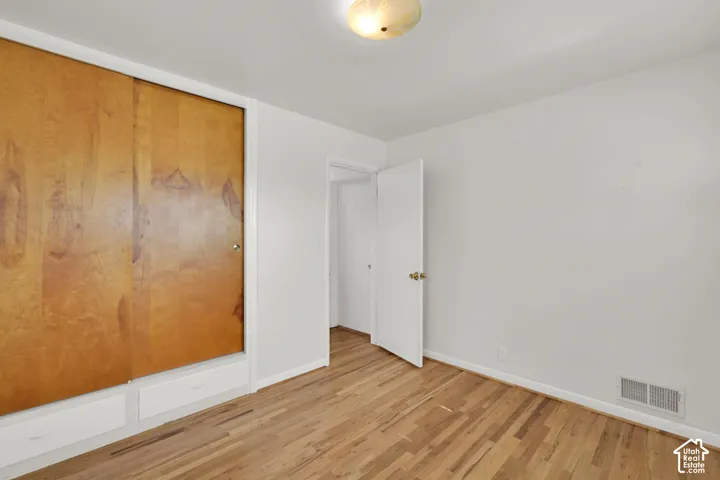 Wood-finish flooring with a built-in closet featuring wood panel doors and integrated drawers