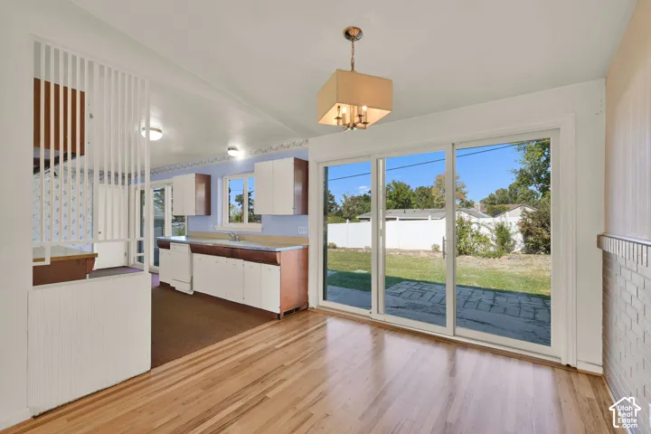 Hardwood flooring, sliding glass doors to the exterior, white brick detailing, and a multi-light ceiling fixture