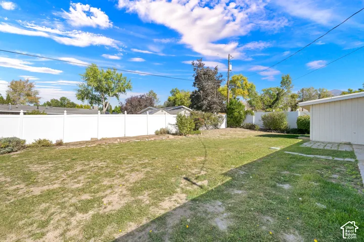 Expansive lawn area, mature trees, white privacy fencing, and a concrete patio
