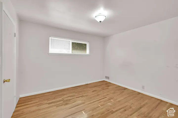 Wood-finish flooring, white walls, and a single window with blinds
