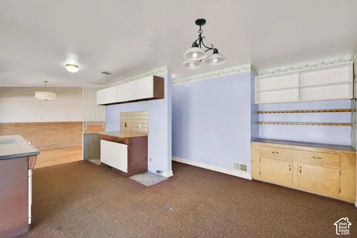 Built-in cabinetry with open shelving, recessed built-in shelving, and a built-in countertop with tiled backsplash