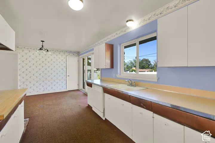 Kitchen featuring a double basin sink, white cabinetry, a built-in dishwasher, and a sliding glass door