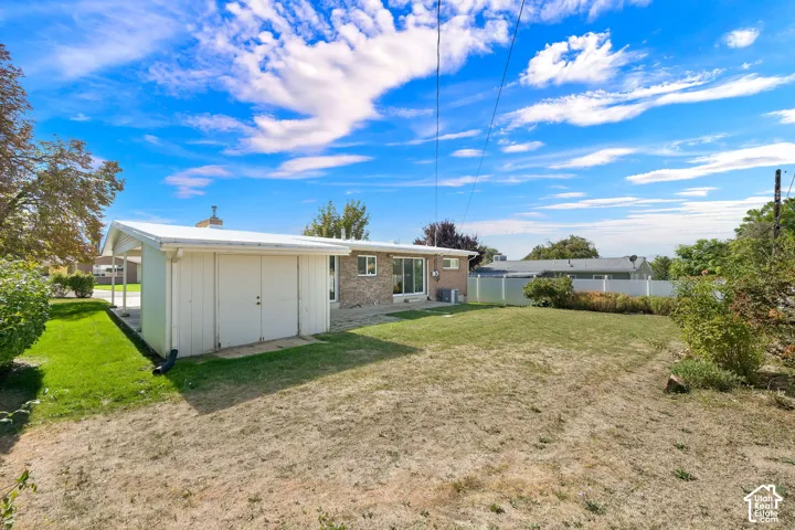 Spacious backyard with a detached storage shed, lush green lawn sections, and mature perimeter landscaping