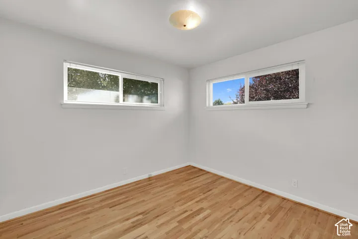 Light wood-finish flooring, white walls, and a semi-flush ceiling light fixture