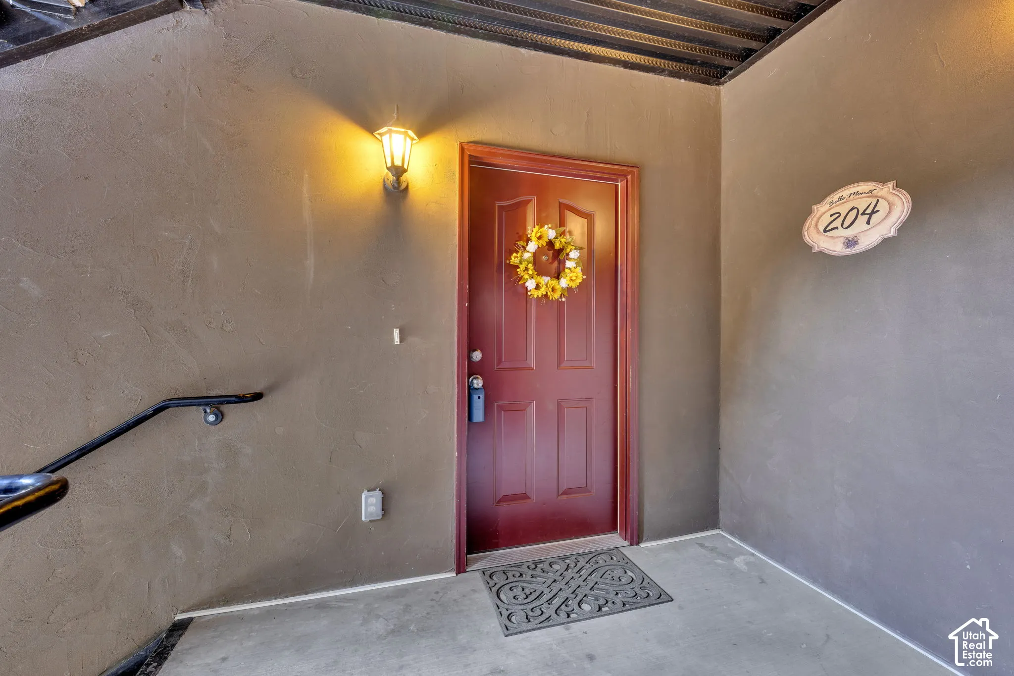 Entryway with an overhead light fixture, a dark wood-finish door, and a black metal handrail