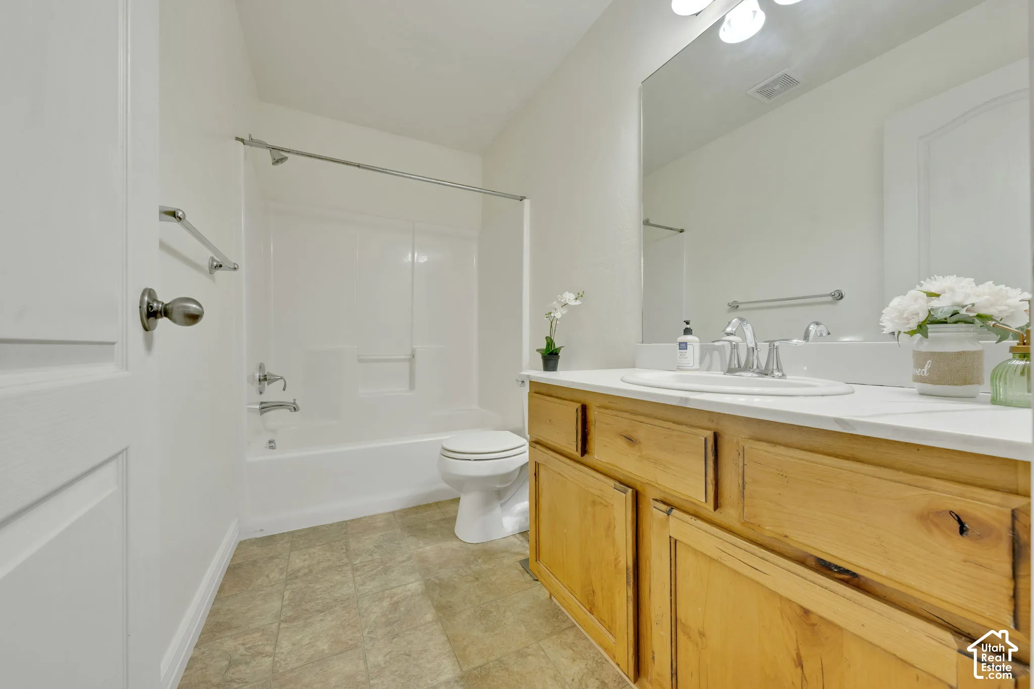 Bathroom featuring a wood-finish vanity with an integrated sink, a white countertop, and a full-width mirror