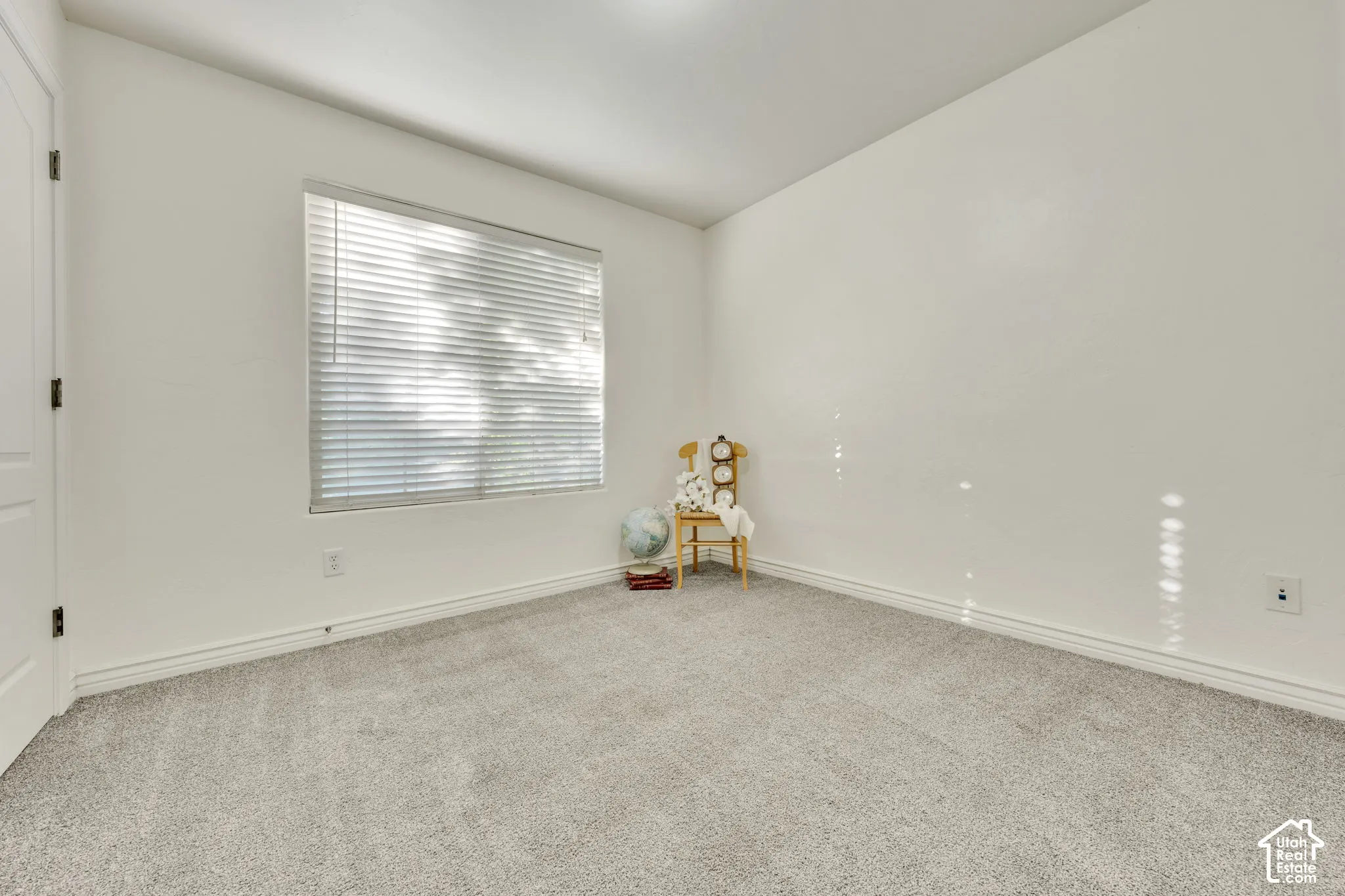 Light gray carpeting, white painted walls, and a single window with horizontal blinds