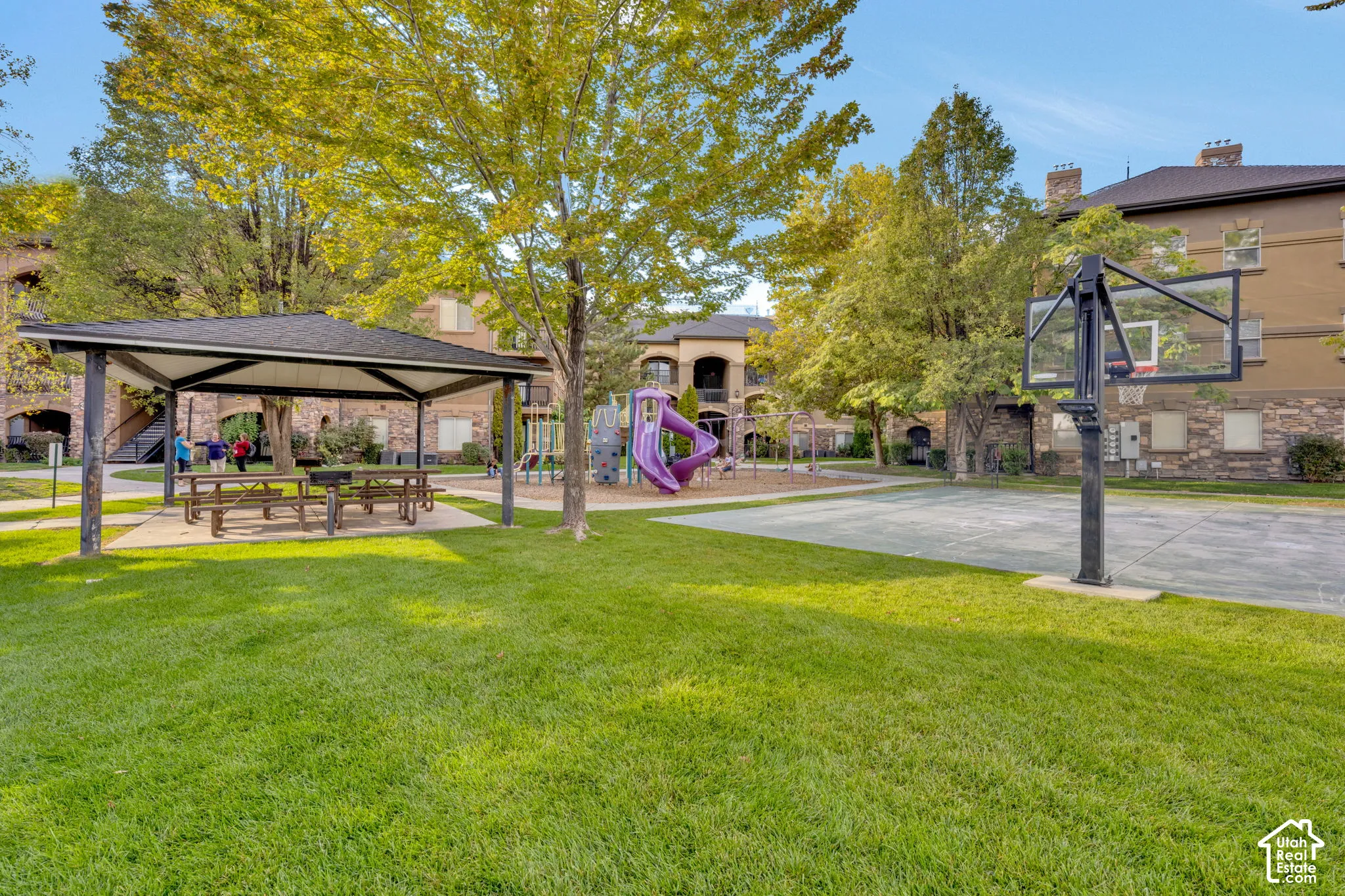 Expansive grassy area with a covered picnic pavilion, picnic tables, and a basketball court