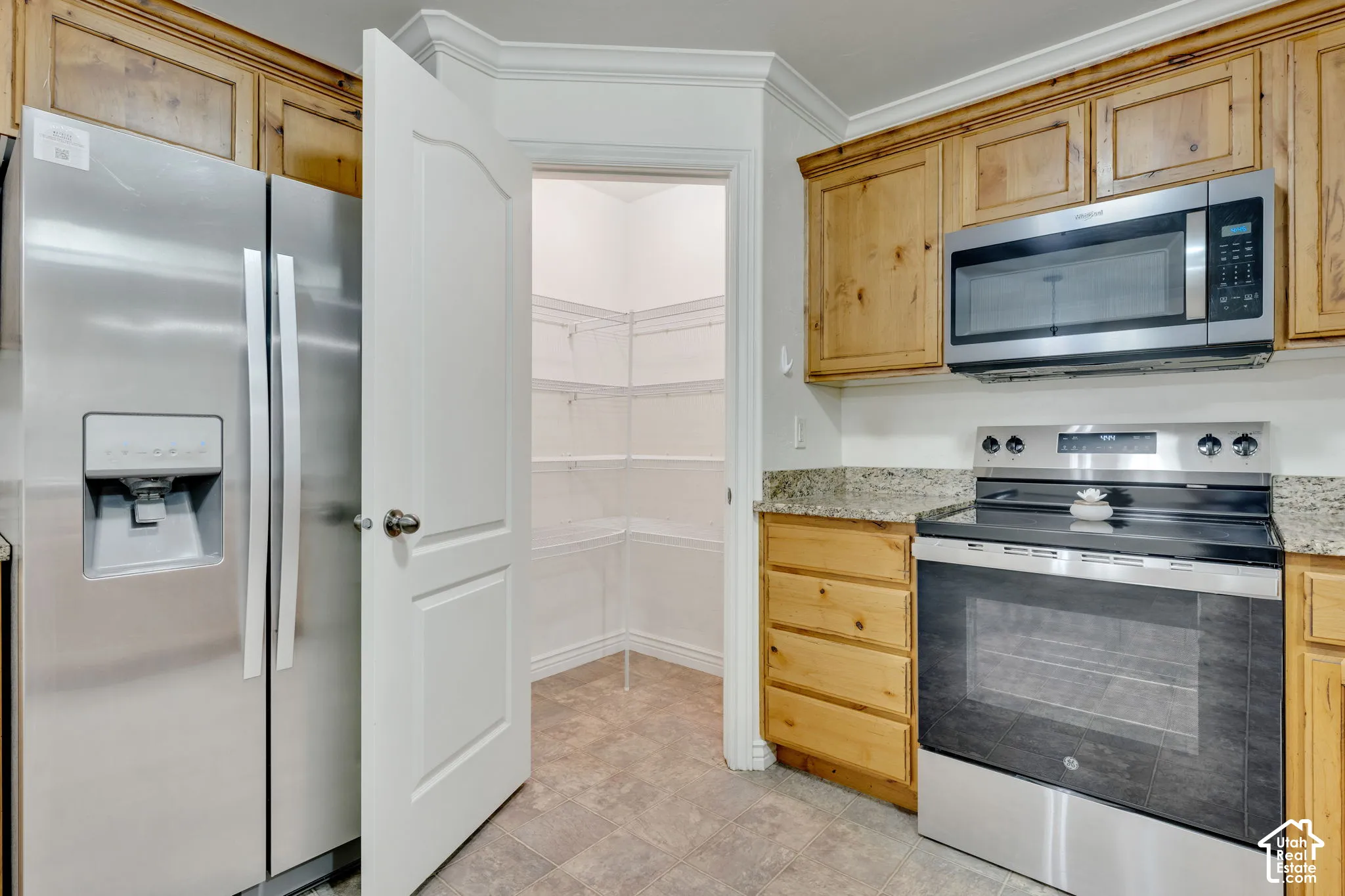 Stainless steel appliances, wood cabinetry, granite countertops, tile flooring, and a walk-in pantry with wire shelving